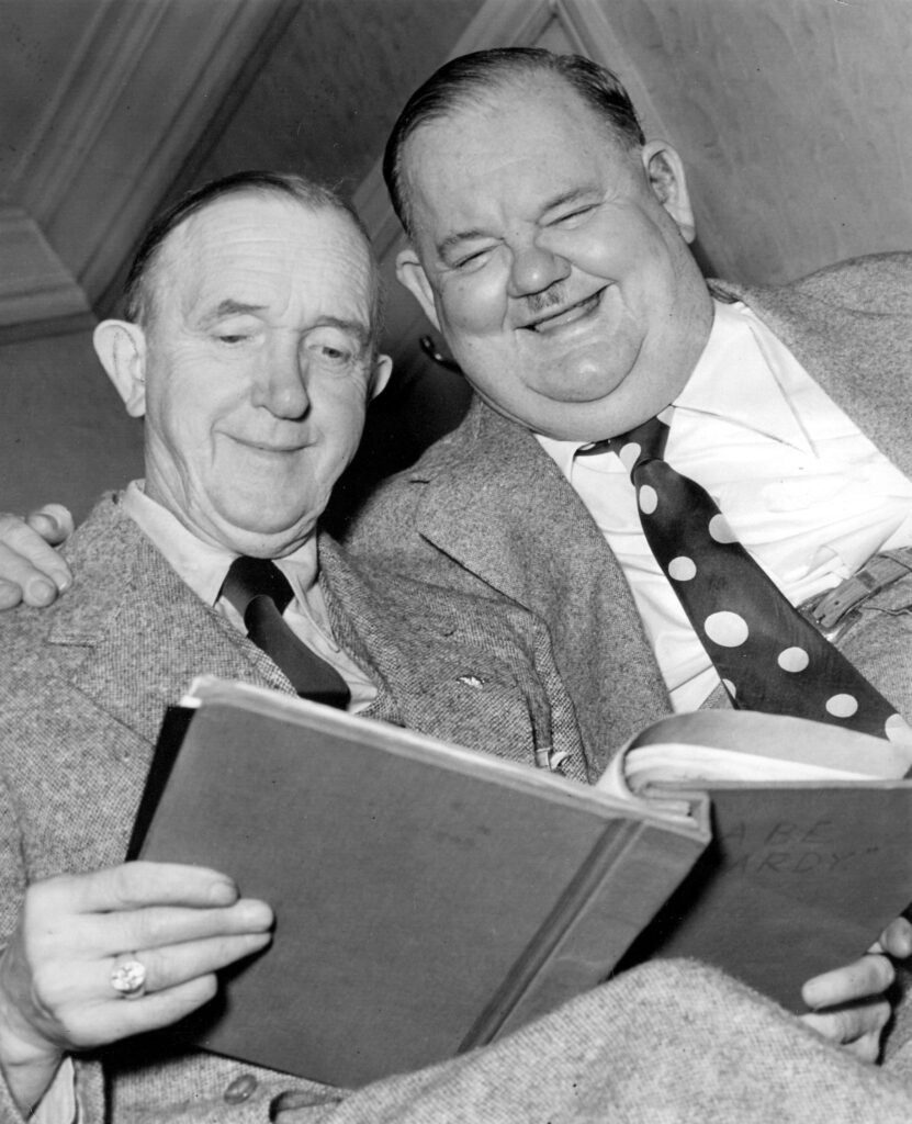 Laurel and Hardy reading Hardy's folder of their stage scripts